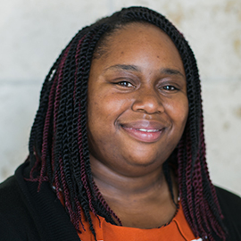 Headshot of Jaslyn Greene - smiling woman with braids and orange blouse