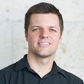 Photo of Jeff Hodson - smiling man in black polo against stone wall