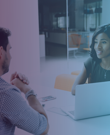 Two adults having a conversation while interacting with a laptop