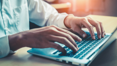 close up of a man's hands at a laptop